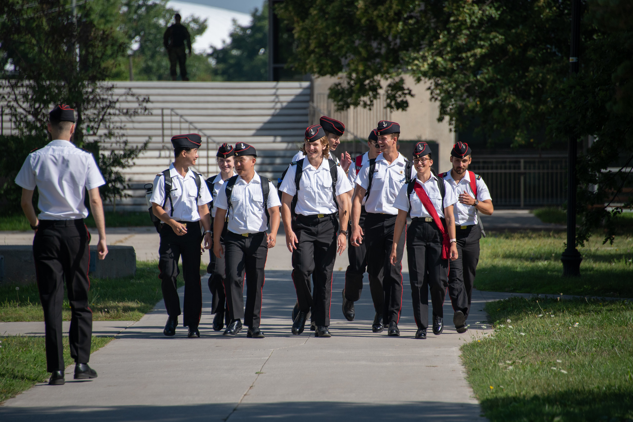 Nine N/OCdts in uniform walking on campus between classes.